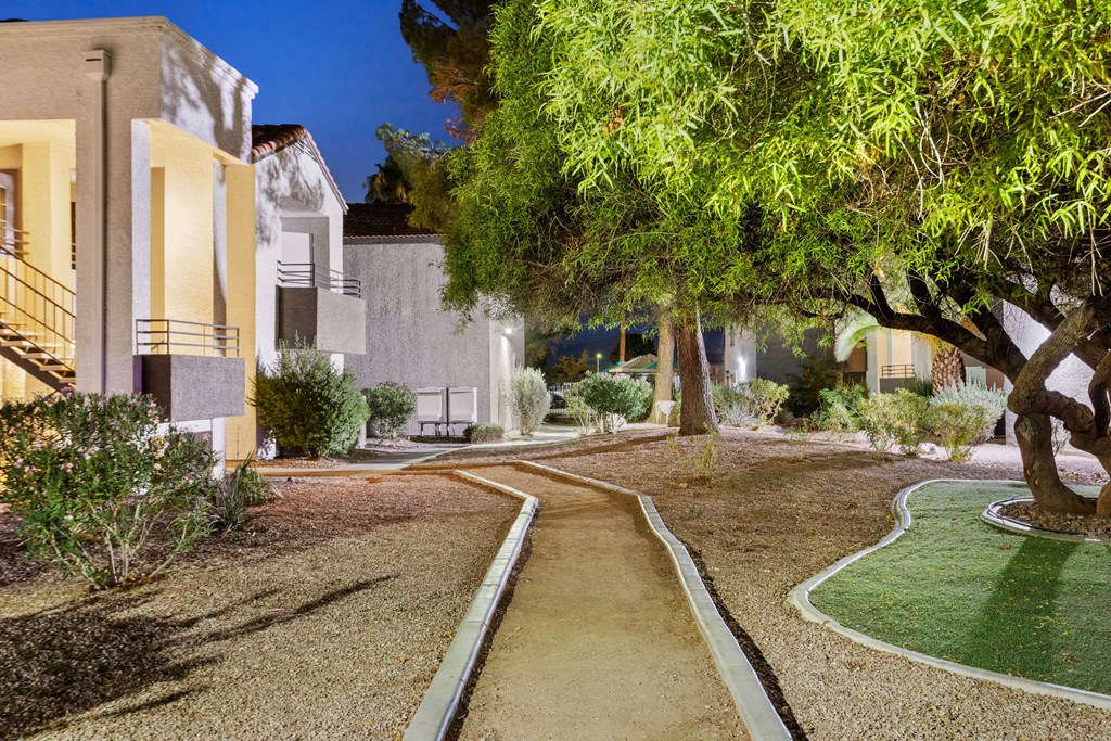 a pathway through a yard with trees and buildings in the background